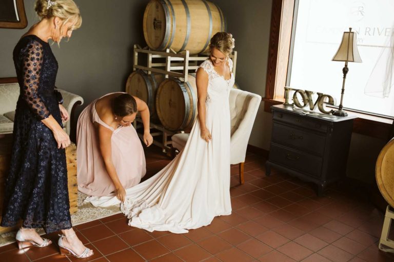 Mother of bride adjusting a dress in the barrel room at Cannon River Winery